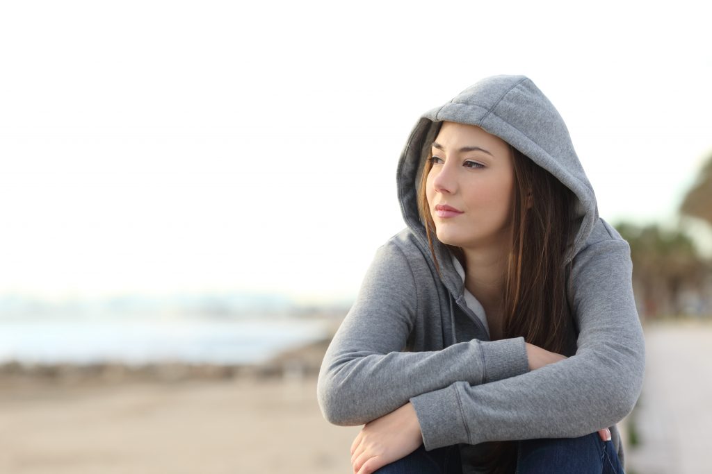 woman sitting at beach looking into distance