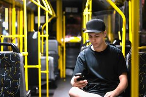 Young male on bus looking at his phone