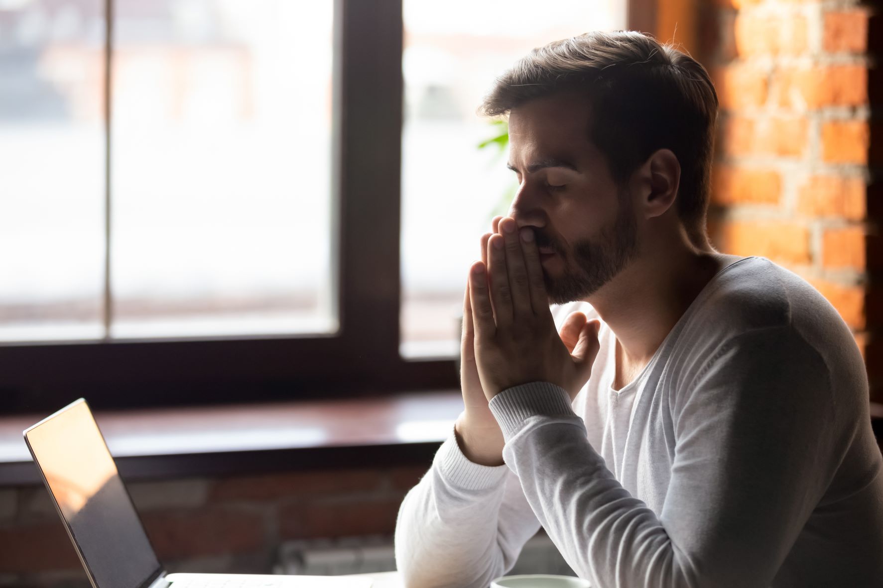 Young man sits at his computer looking worried about his financial situation