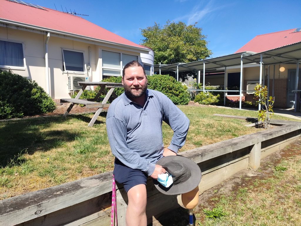 Local actor David lives in supported accommodation with Anglicare. He's pictured sitting smiling in the garden.