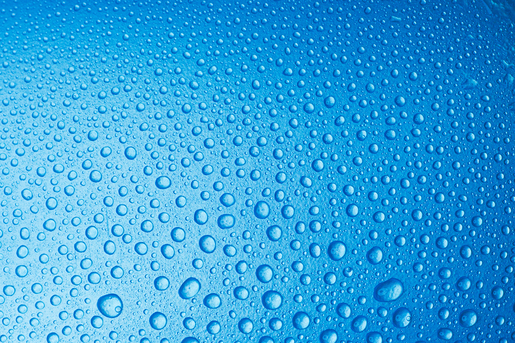 a blue surface which has water droplets on it.